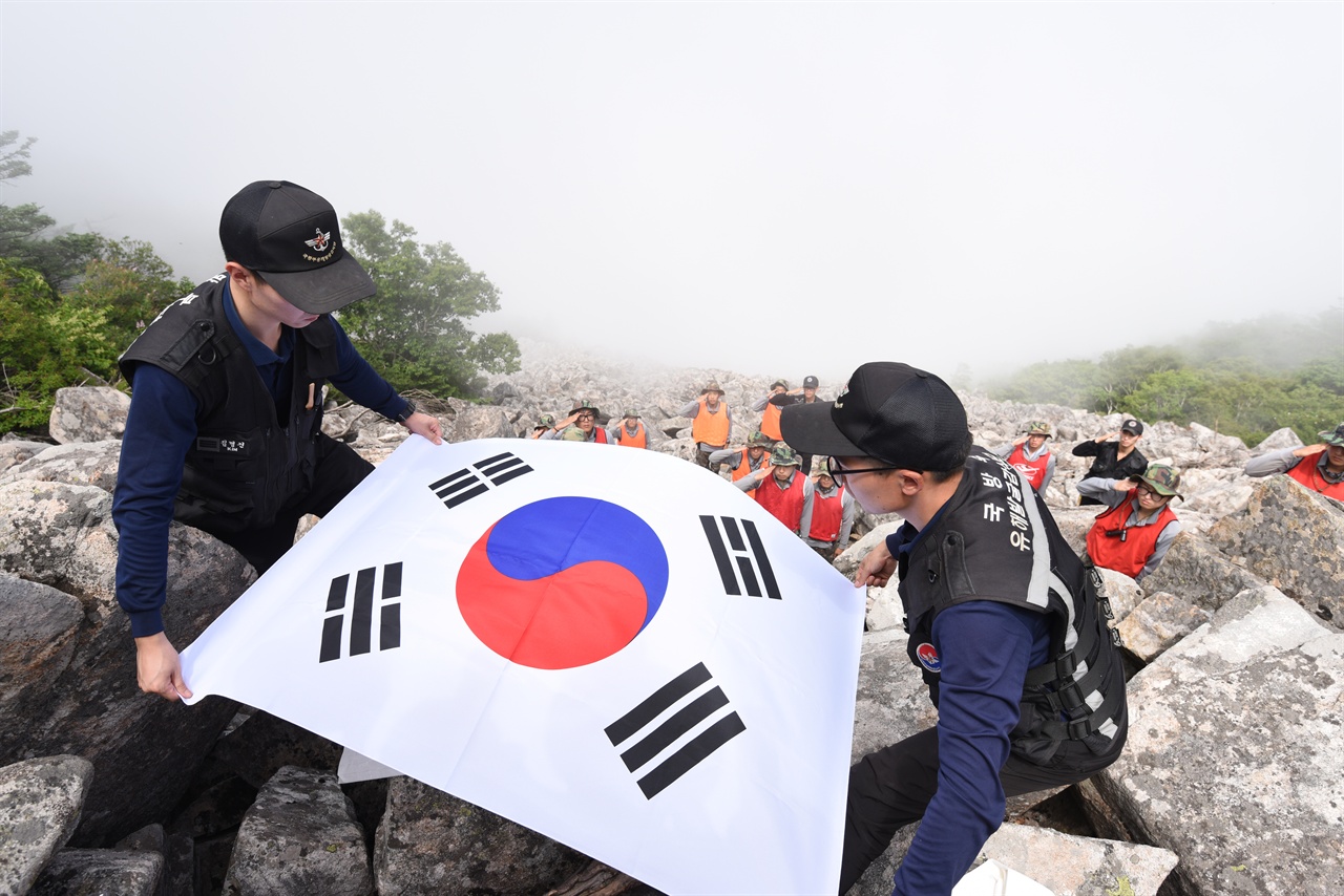 2015년 6월 23일, 강원도 고성에 위치한 설악산 상봉 발굴현장에서 발굴병들이 유해를 모신 관을 태극기로 관포하고 있다.