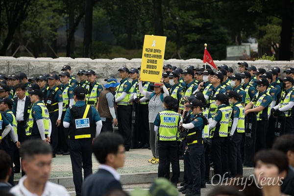 416연대 세월호 유가족들과 시민단체 회원들이 28일 오후 서울 국회 앞에서 야 3당 국회의원들과 함께 세월호특별법 개정안 수용을 촉구하는 기자회견을 열고 있는 동안 한 시민이 경찰 앞에서 1인 시위를 할 수 있다,