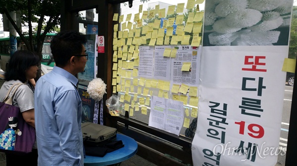 19살 청년의 중학교 친구들이 군포시청 앞 버스 정류장에 꾸민 추모 공간, 아버지가 메모지를 물끄러미 바라보고 있다. 