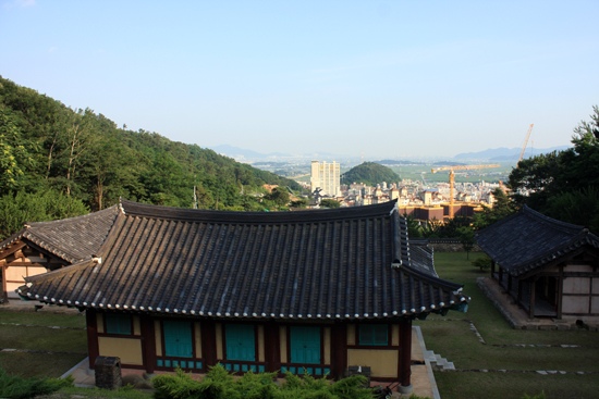  송담서원 강당 지붕 너머로 내려다 보이는 김해시의 풍경. 지평선으로 느껴지는 곳이 허황옥이 배를 타고 나타났던 낙동강 하구 남해 바다이다.