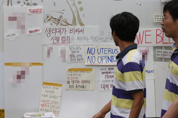 2016년 7월 6일 서울 종로구 인사동길 한 공사장 벽에 '생리대가 비싸서 신발 깔창을 써야 하는 학생들' 등 생리대 가격 인상에 반대하는 문구와 붉은색 물감이 칠해진 생리대가 나붙어 있다.