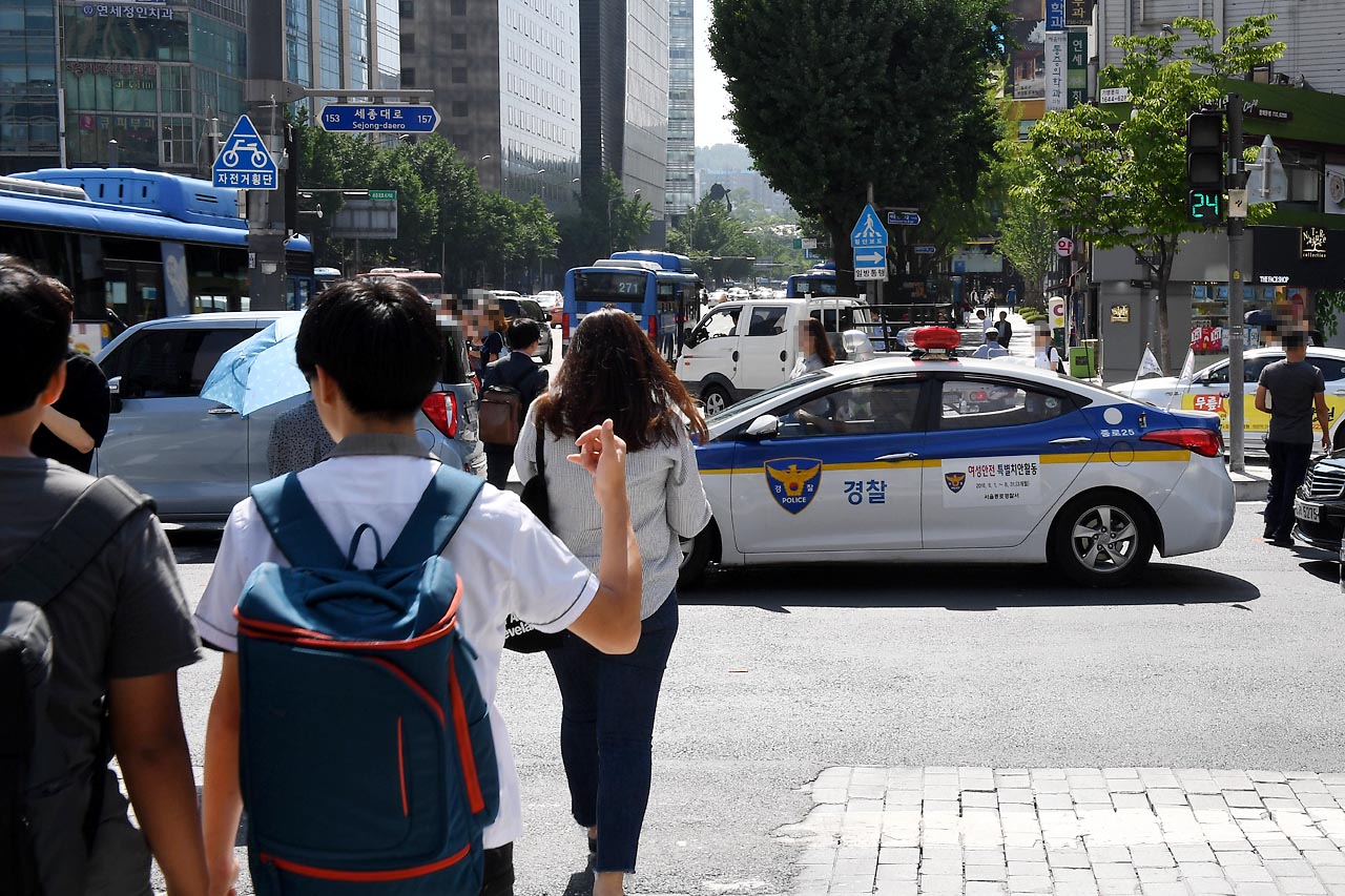 보행자 신호시 횡단보도에 정차한 순찰차 경찰 순찰차 한대가 6일 오후 광화문 광장인근 횡단보도에서 정지선을 넘어 진입해 정차하는 바람에 보행자들이 순찰차를 피해 횡단보도를 건너고 있다.