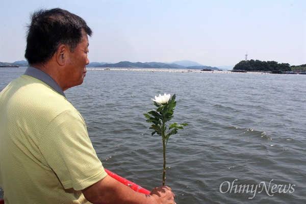 한국전쟁 전후 민간인 학살사건 희생자 '창원유족회'는 9일 오후 수장 현장인 마산만 '괭이바다'에서 '합동 추도식'을 열었다. 사진은 한 유족이 배 위에 서서 국화꽃을 들고 서 있는 모습.