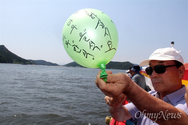 한국전쟁 전후 민간인 학살사건 희생자 '창원유족회'는 2016년 7월 9일 오후 수장 현장인 마산만 '괭이바다'에서 '합동 추도식'을 열었다. 한 유족이 고무퐁선에 바람을 적어 날리고 있다.