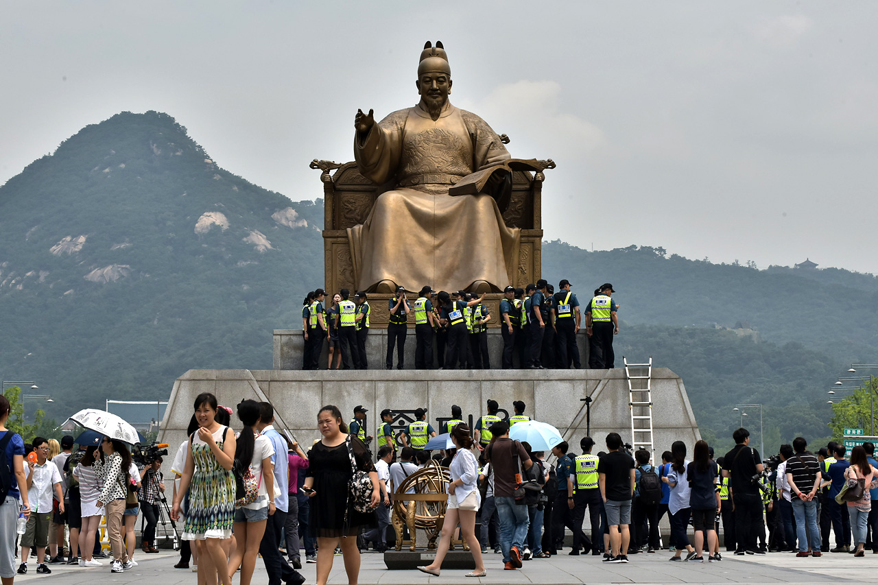  알바노조 소속 조합원들이 12일 오전 서울 세종로 광화문광장에 있는 세종대왕 동상에 올라가 최저 임금 1만원 인상을 요구하는 기습시위를 벌이고 있다.