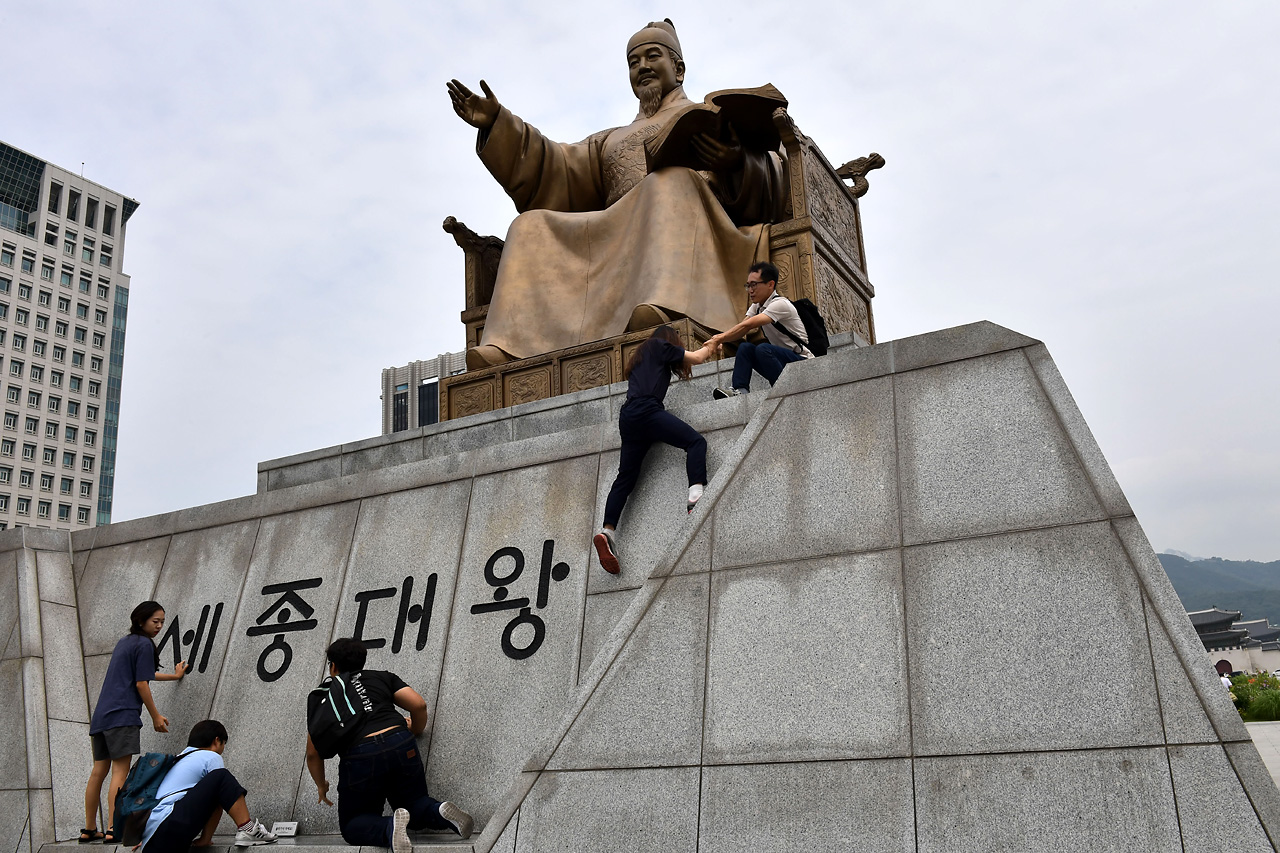  알바노조 소속 조합원들이 '최저 임금 1만원 인상'을 요구하며12일 오전 서울 세종로 광화문광장에 있는 세종대왕 동상위로 올라가고 있다. 