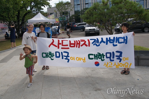 15일 오후 성주군청 앞에서 한 가족이 '대한미국이 아닌 대한민국에 살고 싶습니다'라고 쓴 현수막을 붙들고 있다.