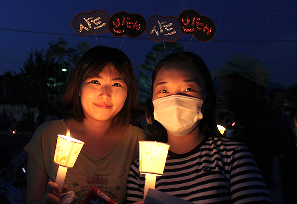 18일 저녁 정부가 사드 배치 예정지로 지목한 성주군에서 주민들이 6번째 사드 배치 반대 촛불집회를 벌였다. 이날 집회에 참석한 이은정(34)씨와 신수빈(26)씨가 직접 만들어 온 머리띠를 쓴 채 촛불을 들고 있다.  