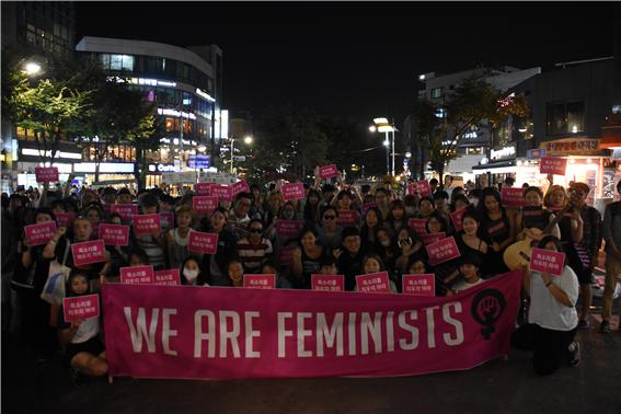 집회 참석자들이 "we are feminists"라는 현수막과 손피켓을 들고 있다