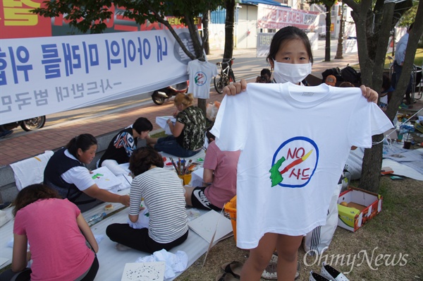 엄마들이 22일 성주군청 앞에서 흰색 티셔츠에 사드 반대 그림을 그리자 어린 학생도 따라나와 함께 그린 티셔츠를 들어보이고 있다.
