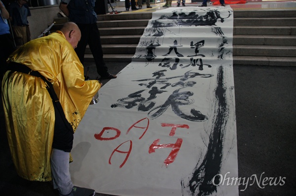 해선 스님이 24일 오후 성주군청 앞에서 열린 사드 배치 반대 촛불집회에서 대형 천에 달마도 그림과 함께 '성주군민 대동단결', '사드 반대' 글을 쓰고 있다.