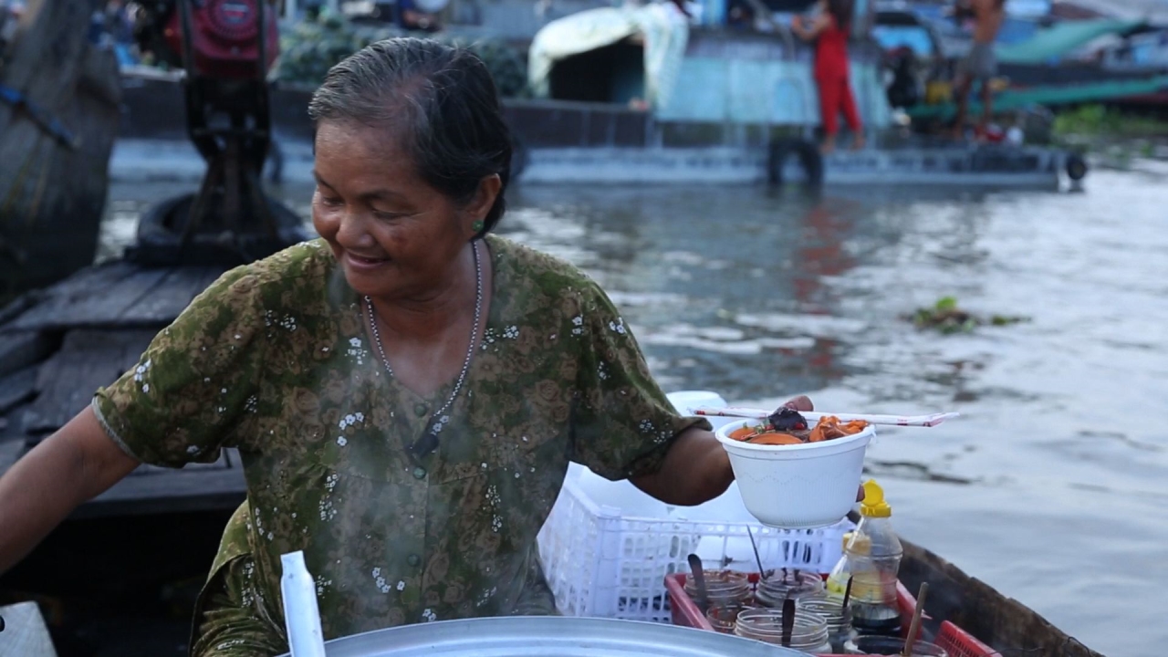 메콩강에서 쌀국수를 팔고 있는 띠엡 할머니 출렁이는 배 위에서 할머니가 방금 만 국수 한 그릇을 건네고 있다.