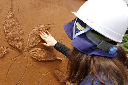 목포대학교에서 열린 흙건축 여름 캠프 참가자들이 미장을 한 벽면에 문양을 내고 있다. 지난 7월 27일이다.