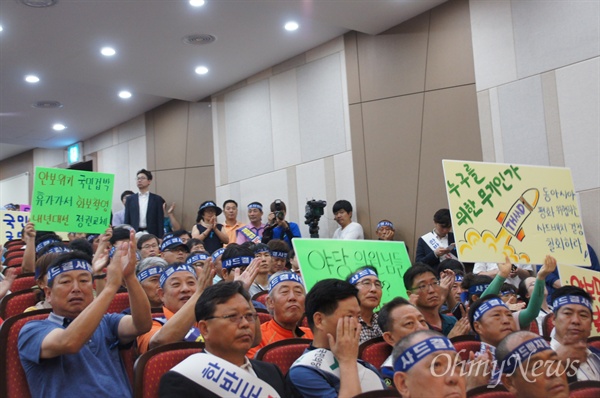  국민의당 국회의원들이 사드 배치가 확정된 경북 성주를 찾아 주민들과 간담회를 가진 가운데 주민들이 피켓을 들고 앉아 있다.