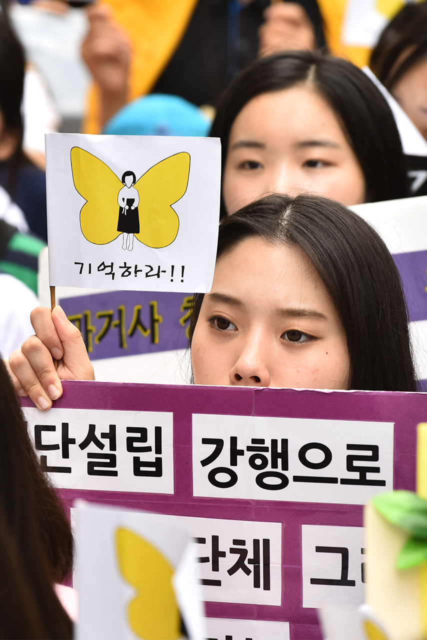  방학을 맞이한 중고등학생들을 비롯한 시민 등 약 1천여명은 3일 오후 서울 종로구 구 일본대사관 앞에서 열린 '제1242차 일본군 위안부 문제해결을 위한 정기 수요시위'에 참가한 가운데 한 참가자가 정부의 '화해와 치유재단 설립' 강행을 을비난하는 피켓을 들어보이고 있다.