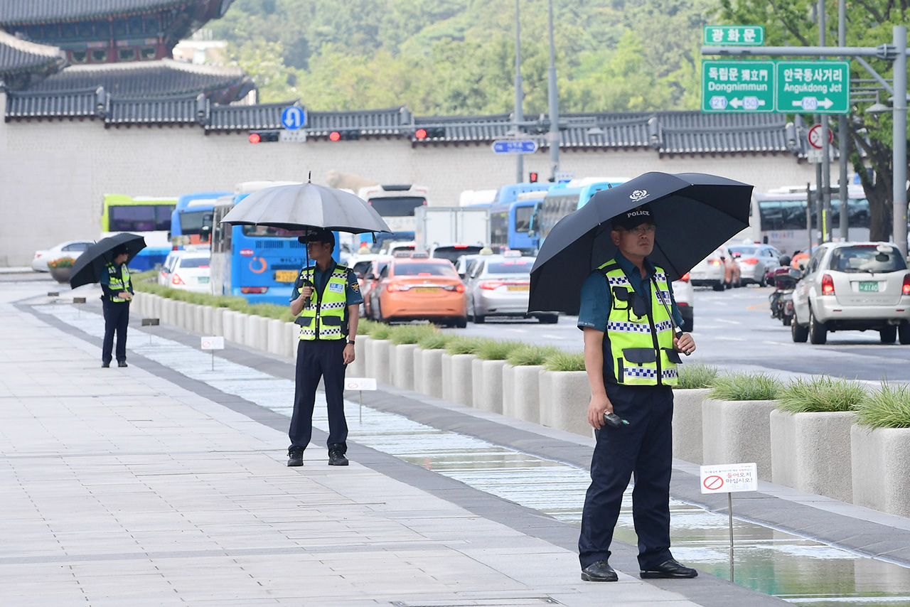 서울지역에 올들어 처음으로 폭염경보가 내려진 4일 오후, 광화문광장에서 경찰들이 강한 햇빛을 피하기 위해 우산을 쓴채 경계근무를 서고 있다.