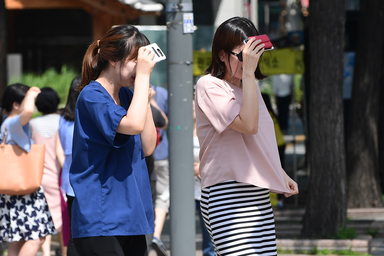  서울지역에 올들어 처음으로 폭염경보가 내려진 4일 오후, 시민들이 핸드폰을 이용해  얼굴에 내리쬐는 강한 햇빛을 가리고 있다.