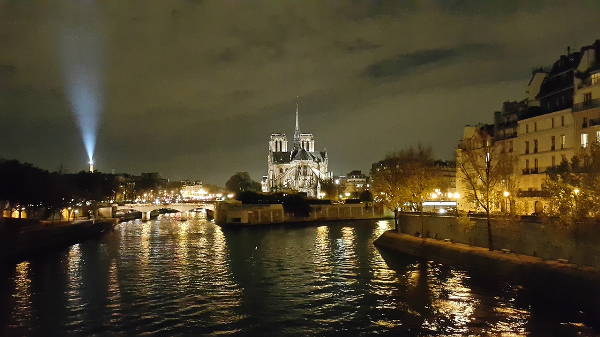 파리 센 강의 야경. 가운데로 노트르담 성당이 보이고, 저 멀리 에펠탑이 쏘아올리는 레이저빔 불빛이 보인다. 