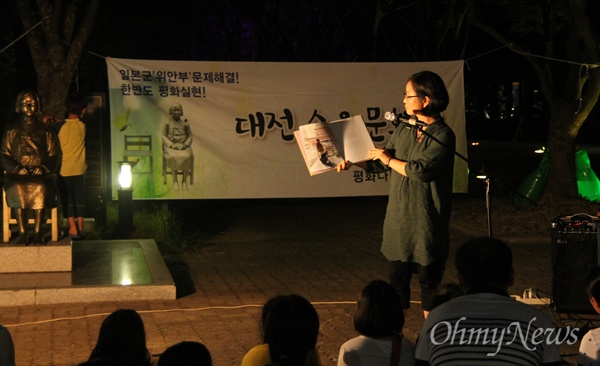 10일 밤 대전평화의소녀상 앞에서 열린 '수요문화제'에서 모퉁이어린이도서관 강영미 관장이 '평화의 소녀상'이라는 제목의 그림책을 읽어주고 있다.