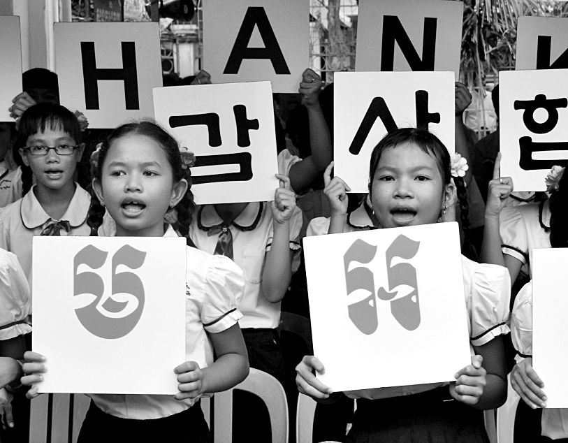 후원물품을 기증한 한국의 독지가의 방문을 앞두고, 감사하다는 한국어와 크메르어 팻말을 들어보이고 있는 캄보디아 초등학생들.