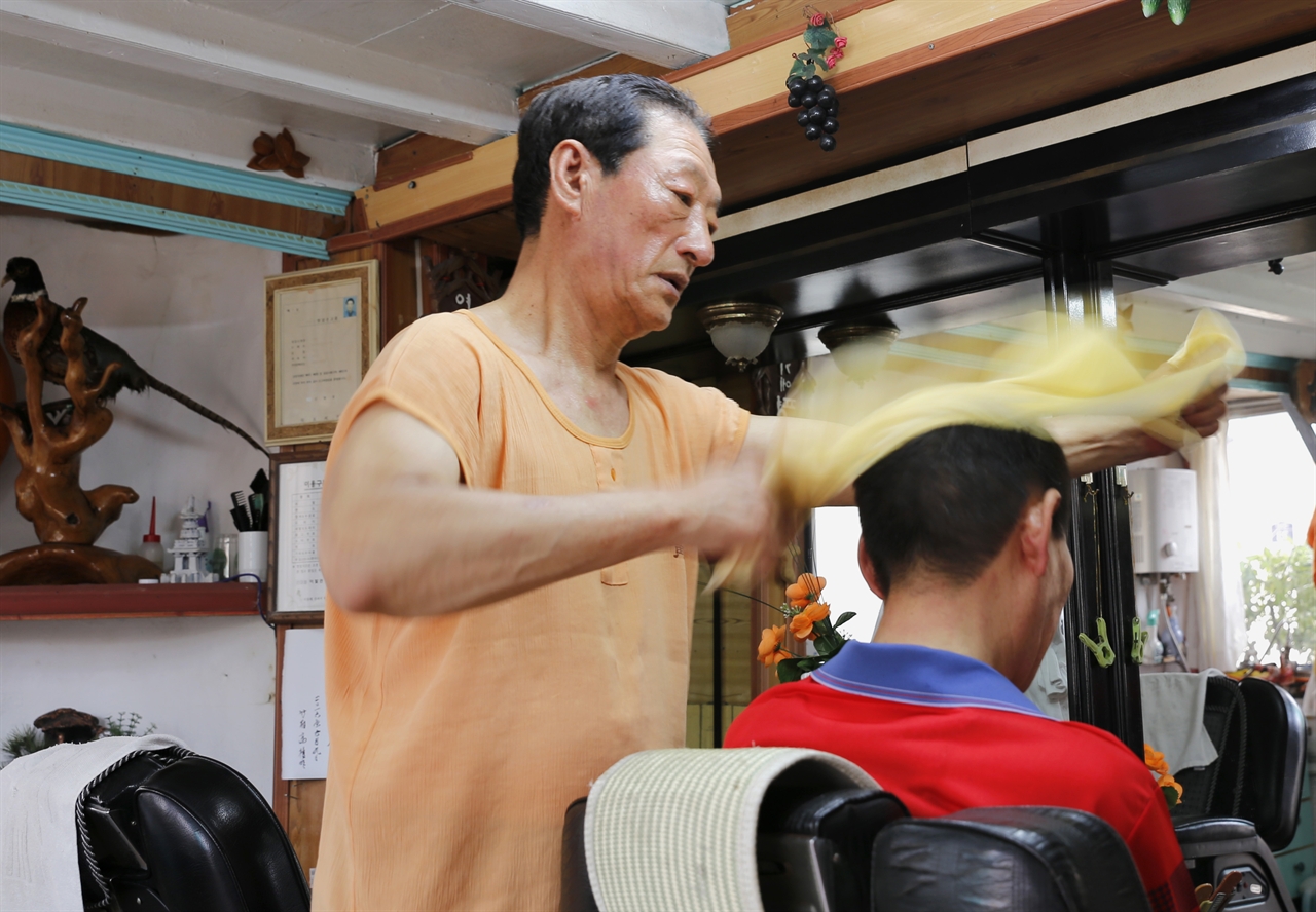 이발사 박행성 씨가 머리를 감겨 준 손님의 머리카락을 수건으로 털고 있다. 지난 7일 모습이다.