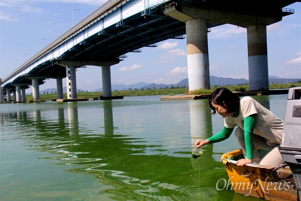 20일 오전 한은정 창원시의원이 창원-밀양 사이 수산대교 아래에서 낙동강 녹조 물을 담아 부어보고 있다.
