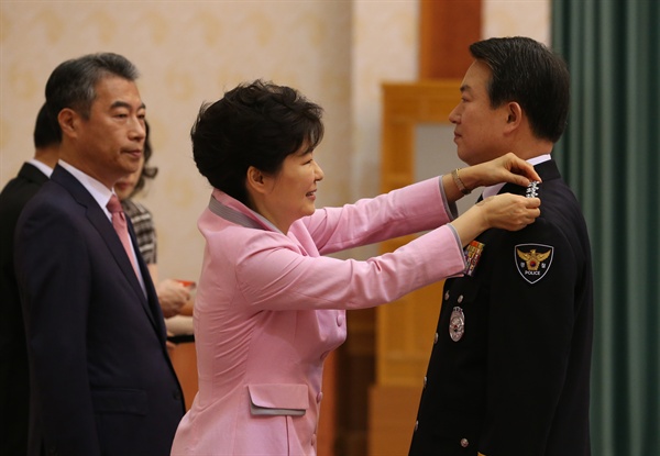 박근혜 대통령이 2014년 8월 27일 오전 청와대에서 강신명 경찰청장에게 진급 계급장을 달아주고 있다.