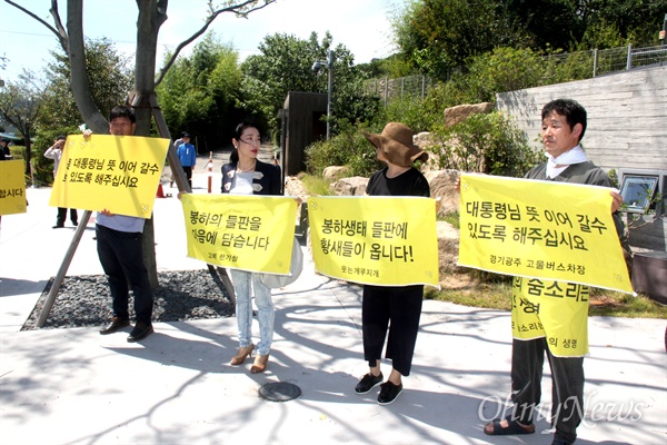 경남 김해시 진영읍 봉하마을 들판의 농업진흥지역 해제에 반대하는 사람들이 31일 손펼침막을 들고 나와 서 있다.