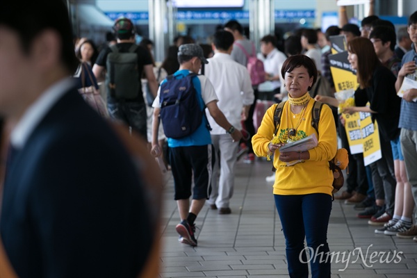  세월호 참사로 아들을 잃은 권미화씨가 13일 오전 서울역 대합실에서 귀성객들에게 노란 기억리본을 나눠주며 인사하고 있다.