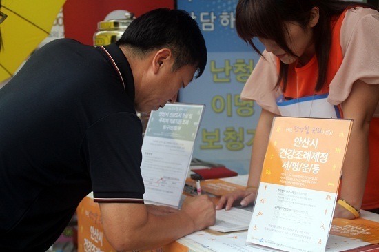 안산의료복지사회적협동조합이 지난 여름 중앙역 광장에서 ‘안산시 건강조례’ 제정을 위해 시민들에게서 서명을 받고 있다.  