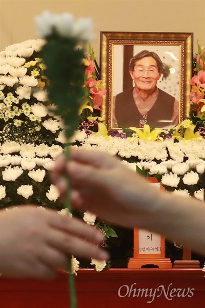 한 시민이 지난 26일 오후 서울 종로구 서울대병원 장례식장 차려진 고 백남기 농민의 빈소를 찾아 조문하기 위해 국화꽃을 건네받고 있다.
