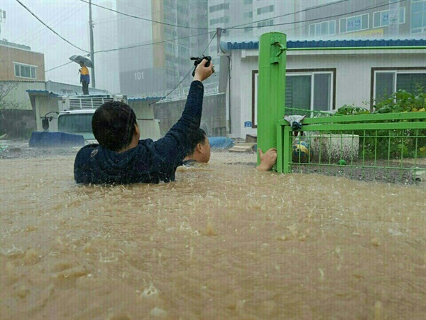 태풍 차바의 영향으로 울산 시내가 물에 잠긴 5일, 중구 태화동의 한 거리에서 주민들이 겨우 걸어서 안전한 곳으로 걸어가고 있다.