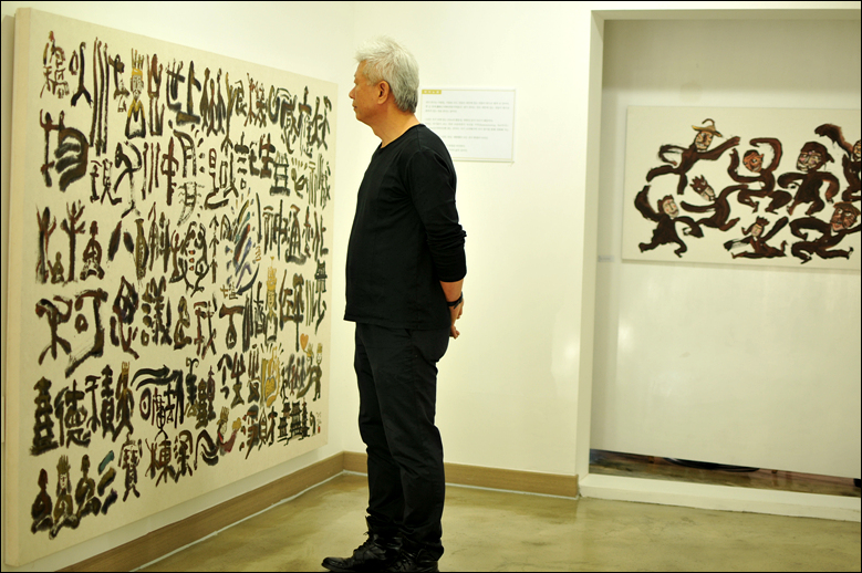 그의 작품이 전시된 '미룸갤러리'를 찾은 박방영 작가. 
작가가 바라보는 그림은 '신통변화'(203×145 2016, 한지 위 혼합 재료).
뒤편의 그림은 '탈춤'(135×68 2014, 한지 위 혼합 재료).