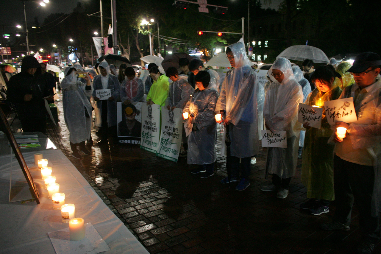 추모 행진 참가자들이 백남기 농민의 영정 앞에서 묵념하고 있다