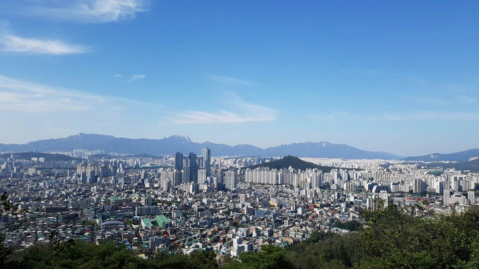  망우산 중턱에서 바라본 서울 북쪽 산들의 모습. 시내 한가운데 봉긋 솟은 봉화산이 보이고 건너편에는 수락산, 불암산, 도봉산, 북한산으로 이어지는 능선이 파노라마처럼 펼쳐져 있다.