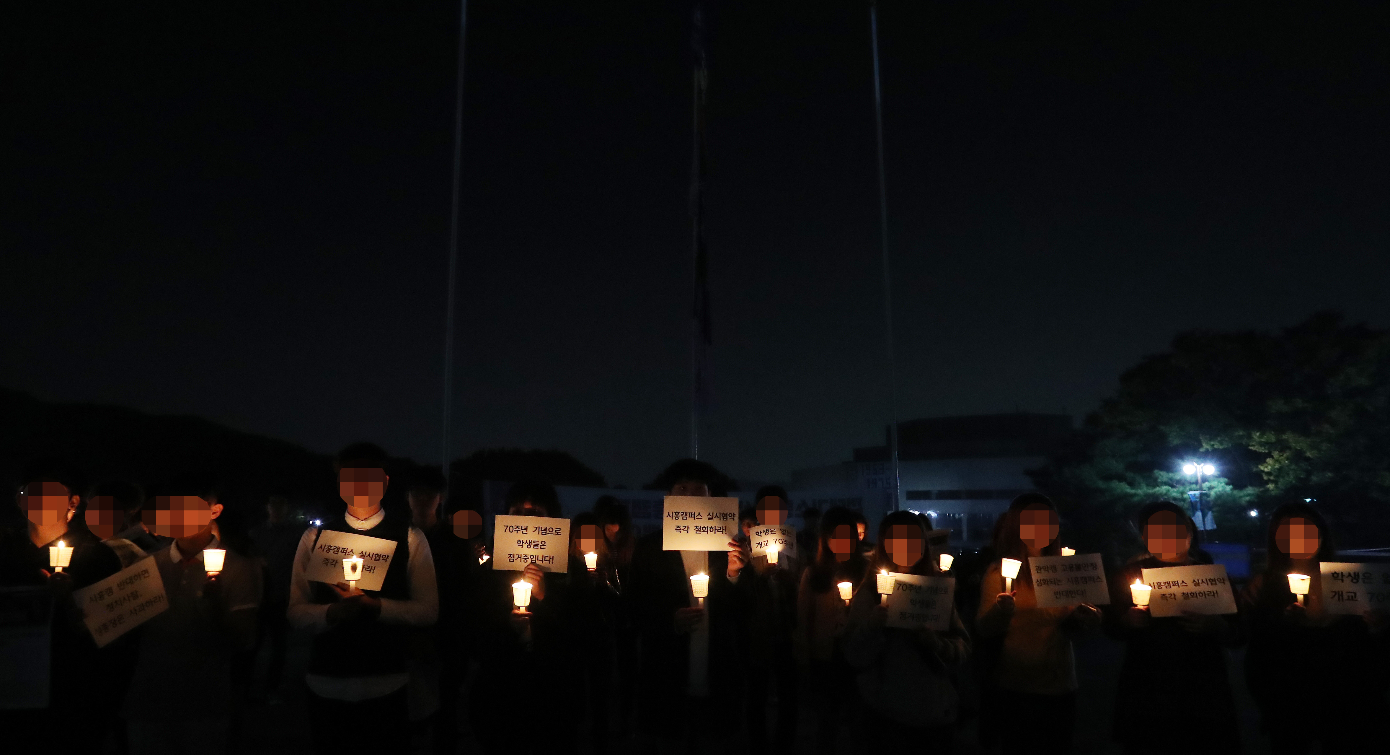 서울대 시흥캠퍼스 추진을 반대하는 학생들이 17일 오후 서울 관악구 서울대 본관 국기게양대에서 교기가 있던 자리에 학생회기를 올린 뒤 촛불시위 하고 있다.