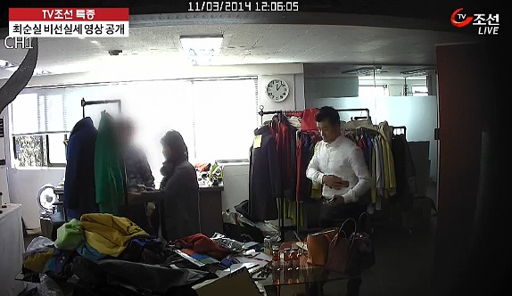 청와대 행정관이 최순실씨에게 휴대폰을 넘겨주기 전에 자신의 옷에 닦고 있는 모습