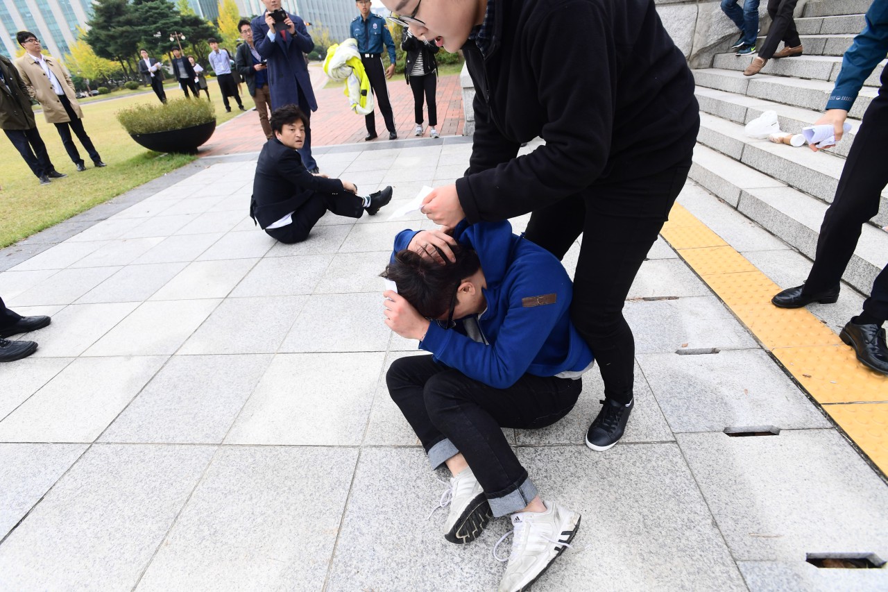 대학생 4여명이 26일 오후 국회본청 계단앞에서 기습 시위를 벌이며 "박근혜 대통령 탄핵"을 외치던 중 국회 방호원에 밀려 계단밑으로 구른후 머리에 고통을 호소하고 있다.