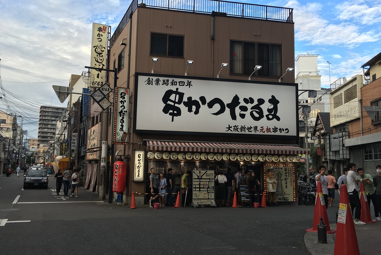 츠텐카쿠(通天閣) 근처 신세카이(新世界)의 쿠시카츠( 串カツ, 꼬치튀김) 전문점 앞에 관광객들이 줄을 섰다. 오사카에서도 특히 신세카이 부근이 쿠시카츠로 유명하다. 간판 아래쪽에 '오사카 신세계 원조 쿠시카츠'라고 쓰여 있다.