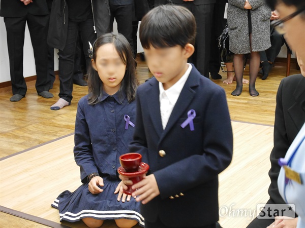  고 신해철의 두 자녀가 고인의 제사상에 술을 올리고 있다. 