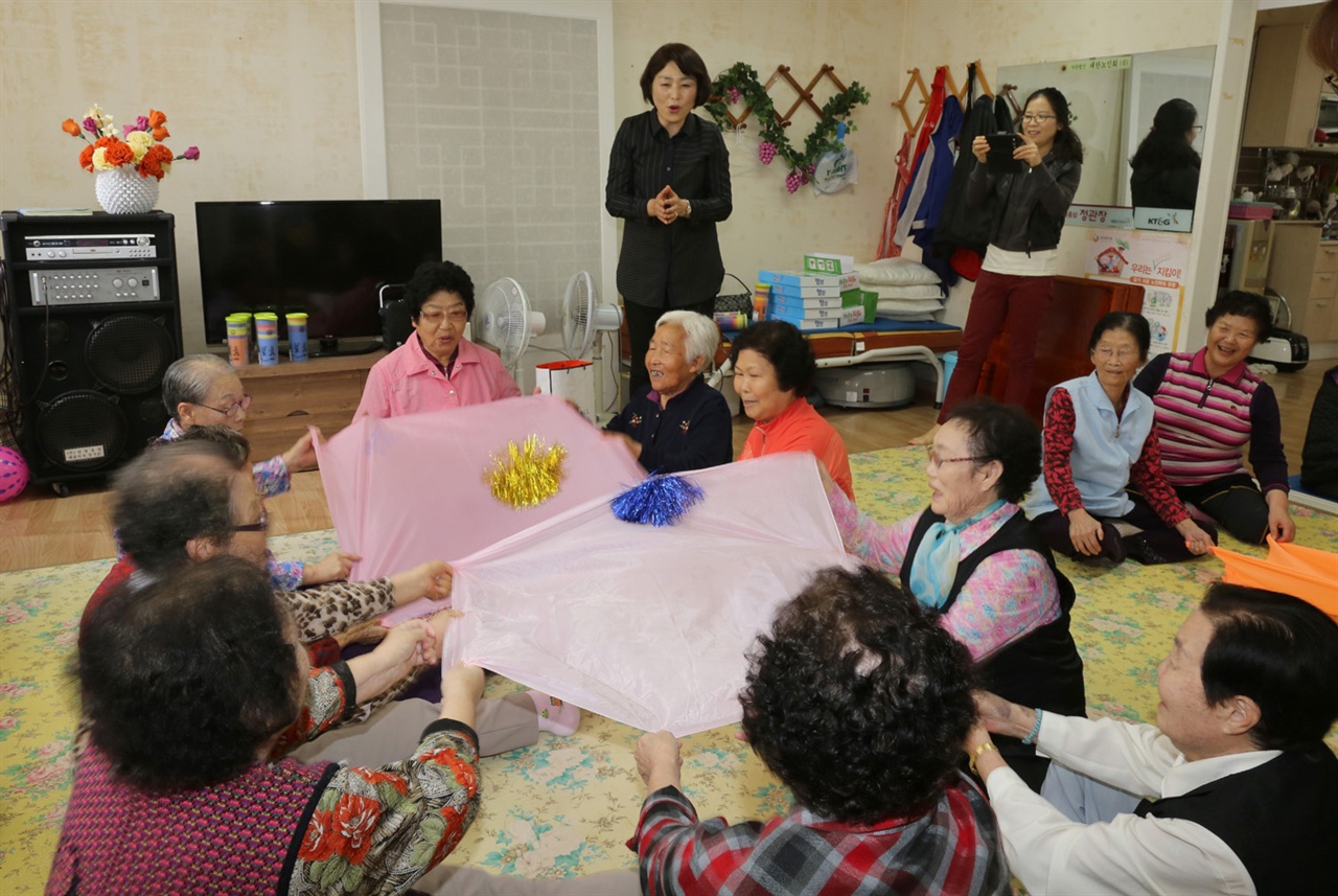 어르신들이 팀을 나눠 보자리로 재기를 치며 옆으로 옮기는, 보자기치기 놀이를 하고 있다. 어르신들의 치매 예방 프로그램의 하나다.