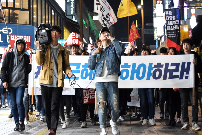 생수병에 쌀을 담아 흔들거나 호루라기를 불며 행진하는 참가자들
