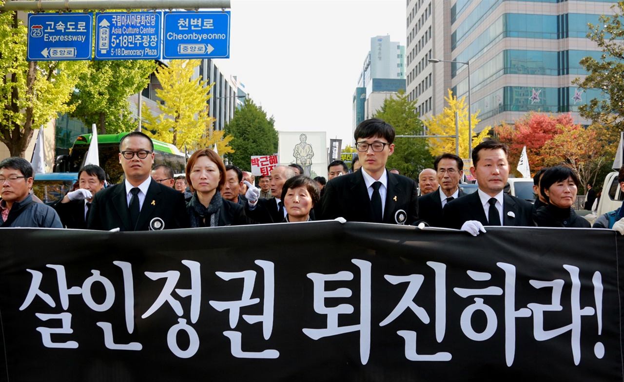  운구행렬 맨 앞에 선 백남기 농민의 가족들이 '살인정권 퇴진하라!'라는 현수막을 들고 행진하고 있는 모습