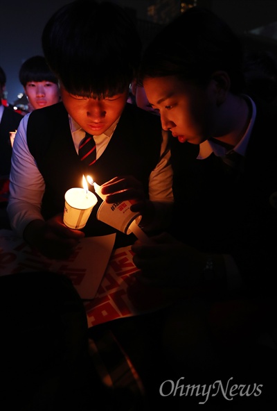 지난 12일 오후 서울 광화문광장에서 열린 민중총궐기 대회에서 청소년들이 '박근혜 퇴진'을 촉구하는 촛불을 붙이고 있다.