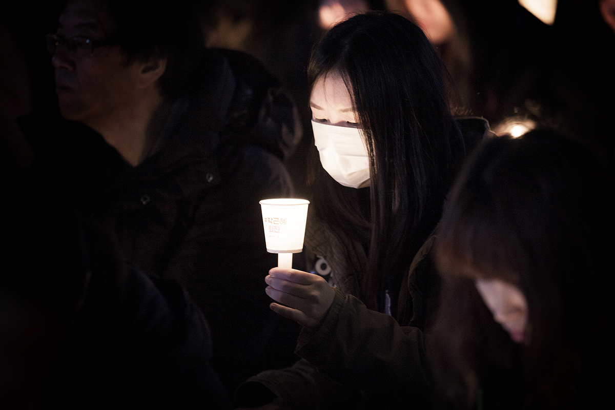 우리의 소원은... 민중총궐기 대회에 참가한 한 시민이, 촛불을 내려다보고 있다.