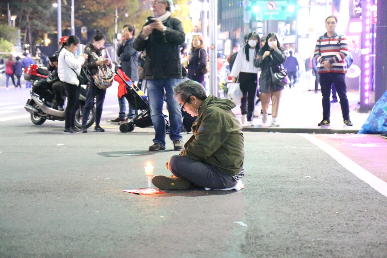 도로에 앉아 가만히 촛불을 바라보는 한 시민