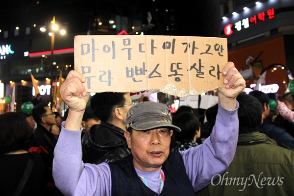 19일 저녁 부산 서면에서 열린 '박근혜 퇴진 시민대회'에 한 시민이 손팻말을 들고 있다. 상자를 찢어 만든 손팻말에는 "마이 무다 (아)이가 그만 무라 빤스 똥살라"라고 써 있었다.