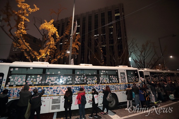 19일 오후 광화문광장에서 열린 박근혜퇴진 4차 범국민행동에 참가했던 시민들이 정부서울청사를 에워싼 경찰버스에 집회 참가자들이 붙인 스티커를 떼내고 있다.