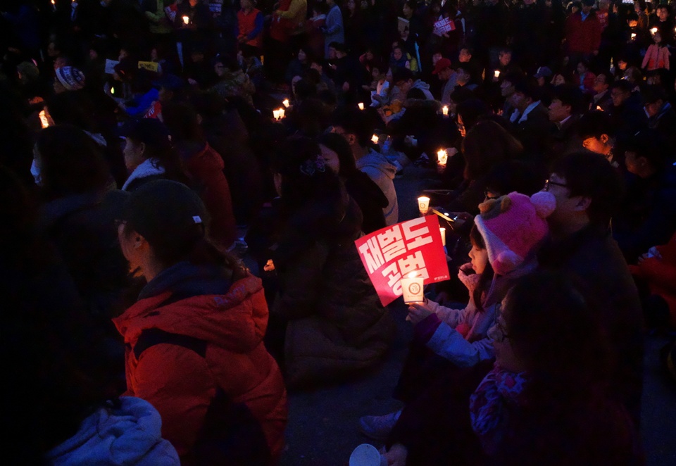 지난 19일 제4차 민중총궐기에서 한아이가 "재벌도 공범"이라는 손피켓과 촣불을 들고 있다