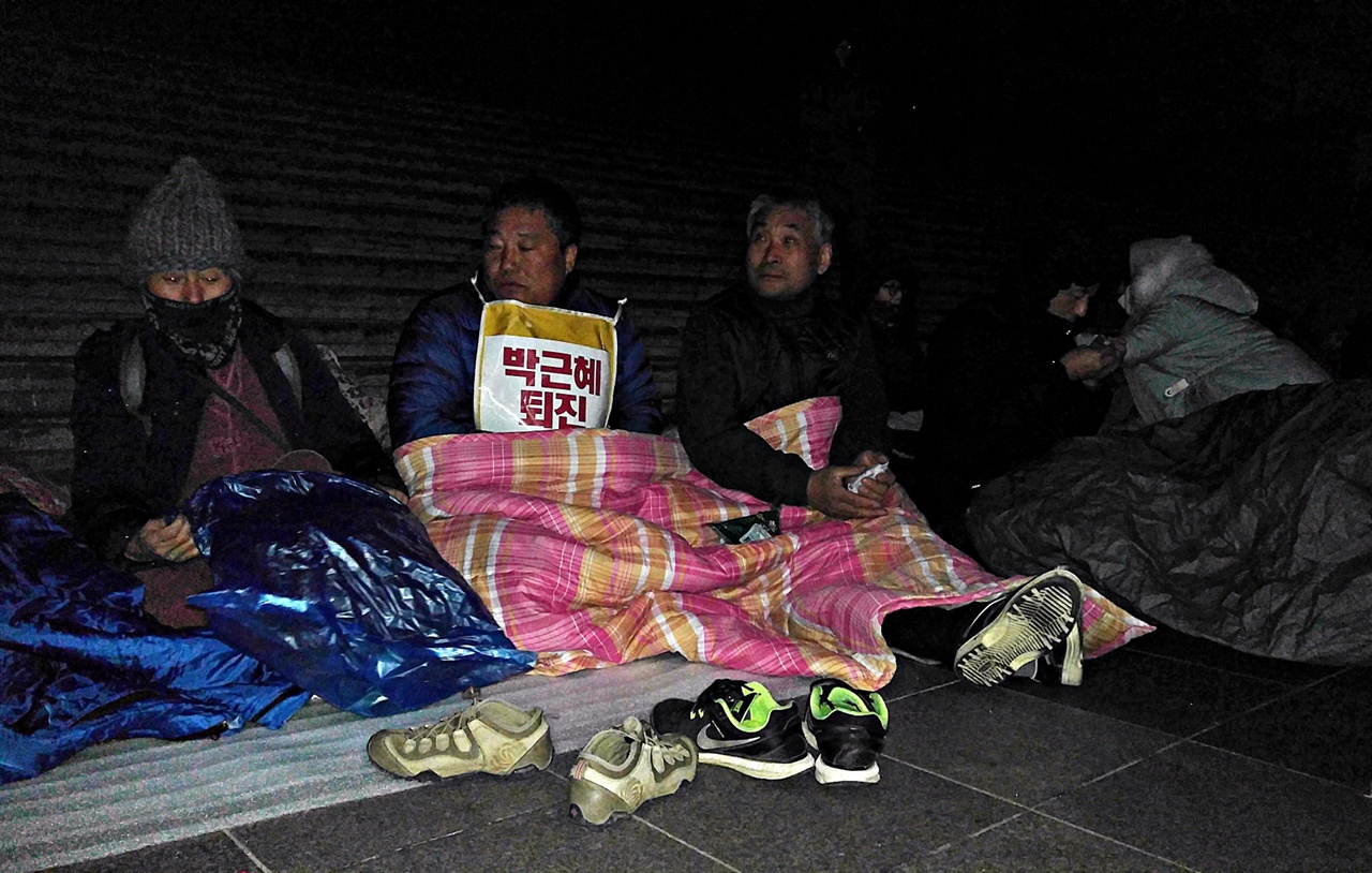  곡성에서 출발해 광화문광장에 도착한 농민들이 추위를 물리치기 위해 은박매트와 마대, 홑이불로 바람을 막고 있다.